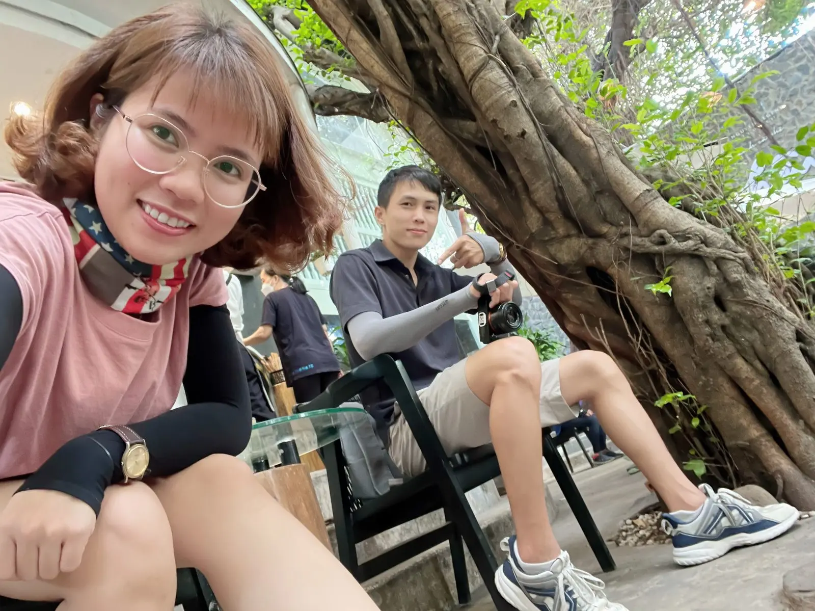 Loo chụp ảnh tự sướng ở quán cà phê dưới gốc cây, Boo ngồi phía sau