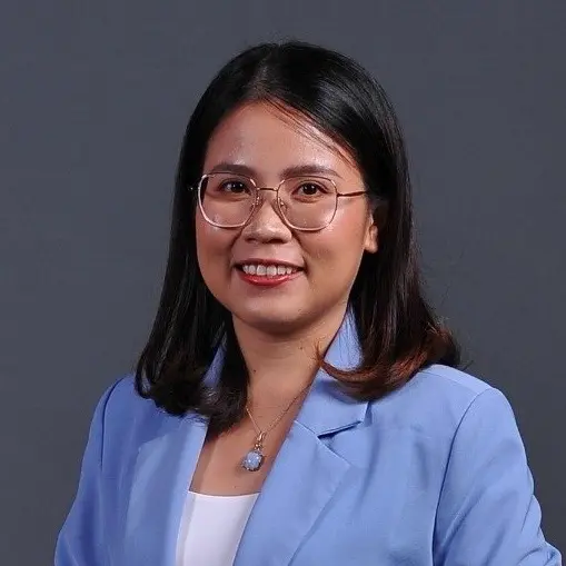MC Lê Trang đeo kính, mặc vest xanh, mỉm cười